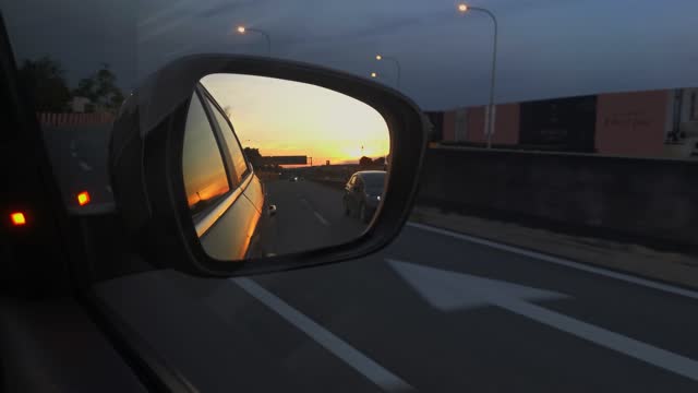 A rear mirror of a car showing beautiful sunset