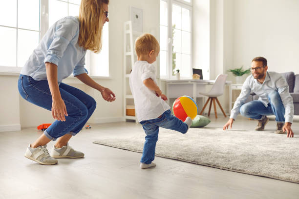 glückliche junge familie mit kleinem sohn spielen ball und spaß zusammen - soccer child indoors little boys stock-fotos und bilder