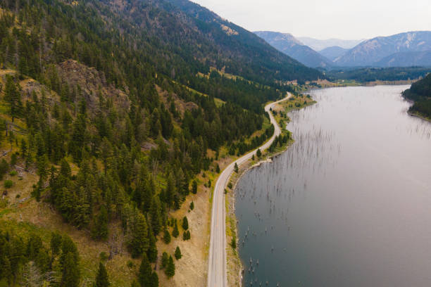 Aerial above winding road next to lake in Montana stock photo