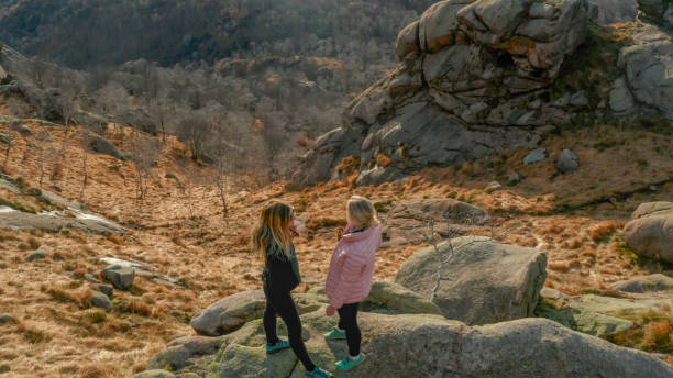 istock Two women stand on edge of boulder above valley 1304054727