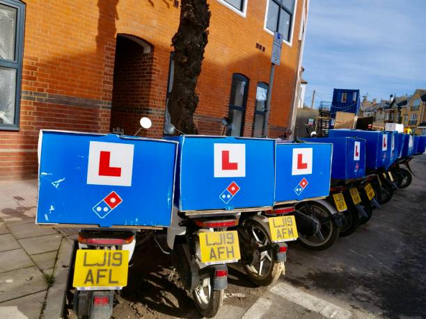 consegna biciclette elettriche del parcheggio domino sul ciglio della strada. - dominos pizza foto e immagini stock