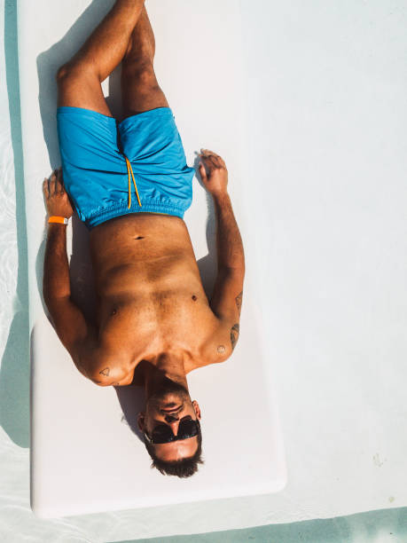 istock Man relaxing on deckchair at poolside 1304057625