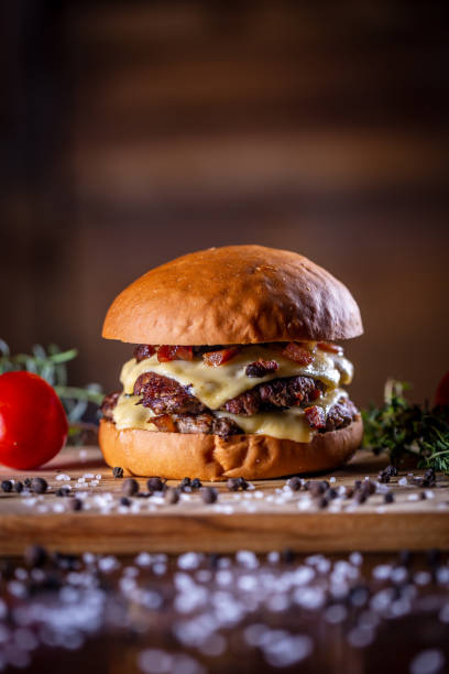 istock Craft beef smash burger with cheese, bacon and sauce on wooden background 1304061993