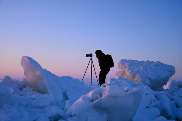 istock Photographer shoots a sunset among the snow-covered hummocks 1304063432