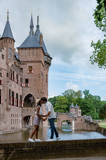 Castle de Haar Utrecht, couple men and woman mid age European and Asian visit De Haar Castle in Dutch Kasteel de Haar is located in Utrecht Netherlands during Spring with flowers in the garden