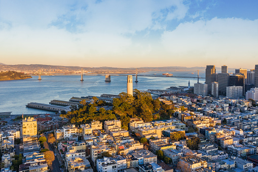 Aerial view of Coit Tower and the San Francisco financial district in the background. Bay Bridge and several landmarks fill the background.