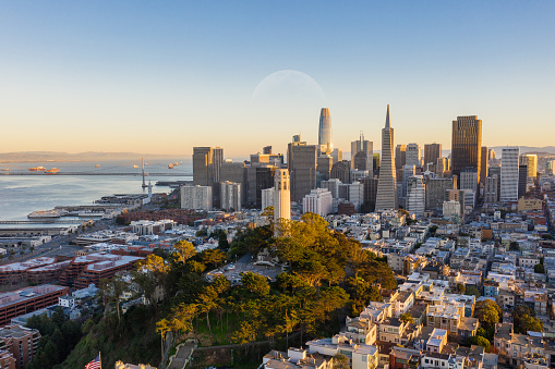 Aerial view of Coit Tower and the San Francisco financial district in the background. Bay Bridge and several landmarks fill the background.