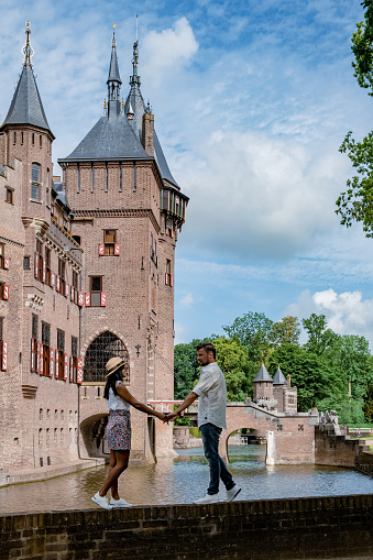 Castle de Haar Utrecht, couple men and woman mid age European and Asian visit De Haar Castle in Dutch Kasteel de Haar is located in Utrecht Netherlands during Spring with flowers in the garden