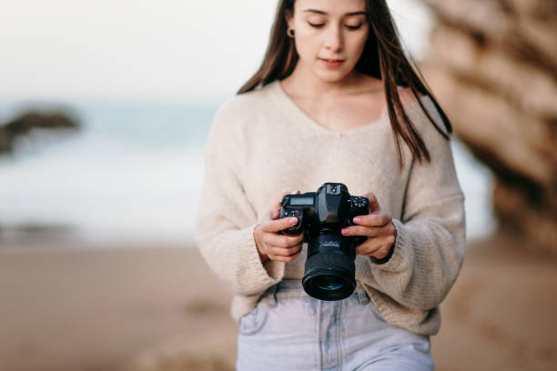 istock Young woman at beach using a DSLR camera 1304064623