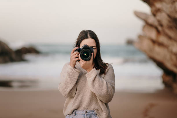 Young woman at beach taking a picture with a DSLR camera