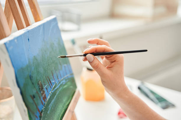 istock Woman with easel and canvas painting at home 1304065708