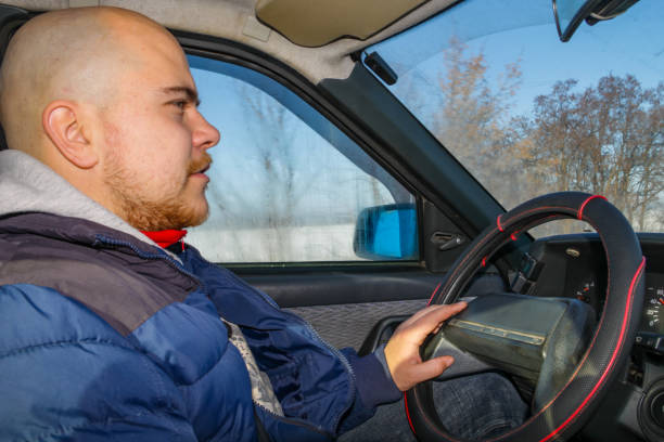 istock Young man driving a car on winter road. Inside view 1304065882