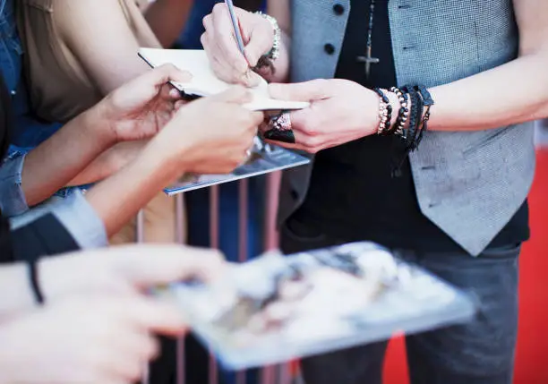 Photo of Celebrity signing autographs on red carpet