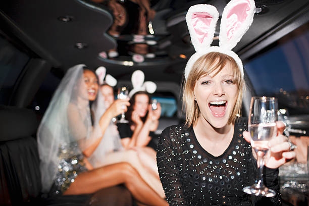 donna nelle orecchie da coniglio bere champagne in limousine - addio al nubilato foto e immagini stock