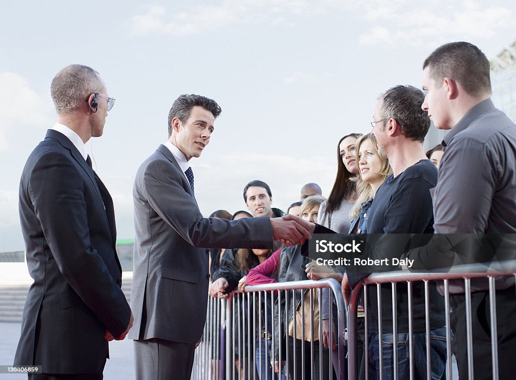 Politician shaking hands with people behind barrier  Bodyguard Stock Photo