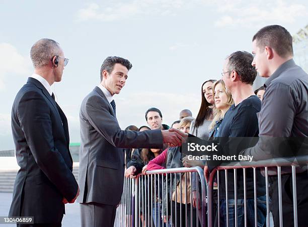 Politician Shaking Hands With People Behind Barrier Stock Photo - Download Image Now