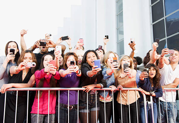 Fans taking pictures with cell phones behind barrier  photo fame stock pictures, royalty-free photos & images