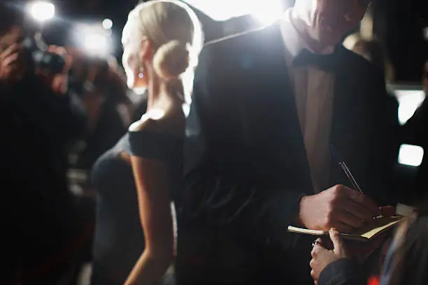 Photo of Celebrity signing autographs on red carpet