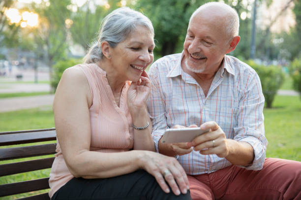 istock Senior couple having fun outside using smart phone 1304068786