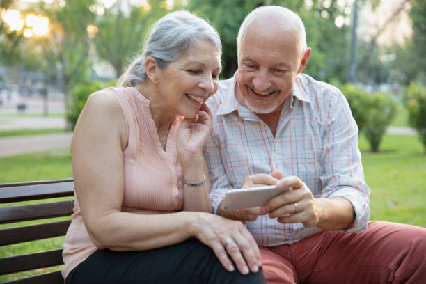 istock Senior couple having fun outside using smart phone 1304068802