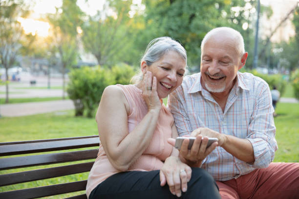 istock Senior couple having fun outside using smart phone 1304069362