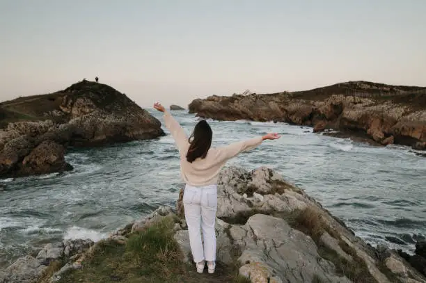 Photo of Young woman with arms raised by the sea