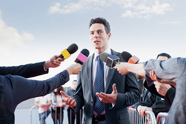 Politician talking into reporters' microphones  pre press stock pictures, royalty-free photos & images