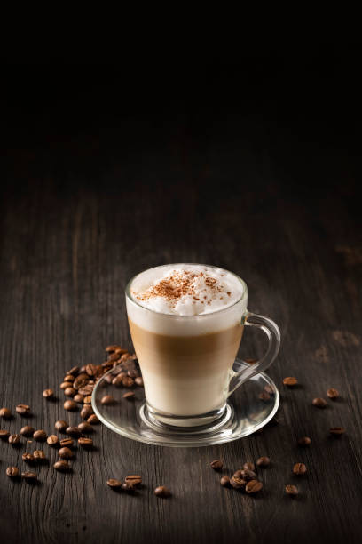 Latte Macchiato Coffee layered with Milk, Roasted Coffee Beans on black wooden background stock photo