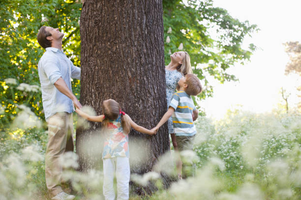 famille debout en cercle autour d'arbre - mother family vertical flower photos et images de collection