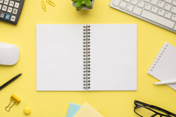 istock Photo overhead of notebook keyboard calculator pen computer mouse notes plant glasses and paper clips isolated bright color backdrop 1304073057