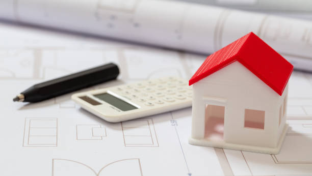 istock Calculator and house model on blueprint background. Construction cost concept. 1304074081