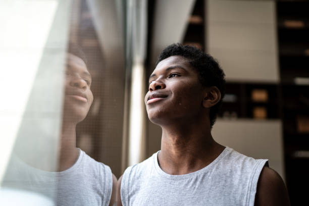 Confident teenager boy looking through the window at home Confident teenager boy looking through the window at home confident boy stock pictures, royalty-free photos & images