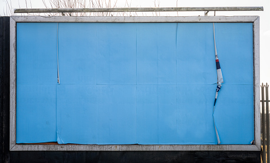 Blank blue paper covering the surface of a large advertising billboard.