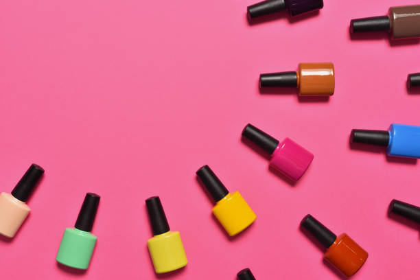 Bottles of nail polish on pink background top view with text space stock photo