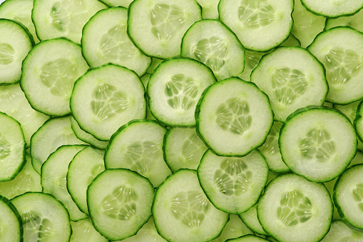 Abstract background of green cucumber slices on white. Top view.