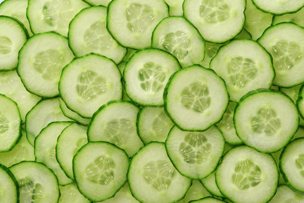 Abstract background of green cucumber slices on white. Top view. stock photo