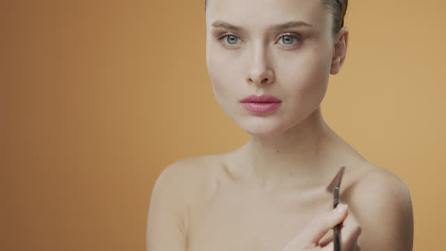 Steps of make-up applying. Beautiful girl with a make-up brush applies a highlighter to the body, collarbone.