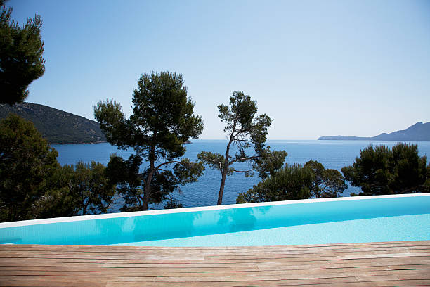 деревья и панорамный бассейн с видом на линию горизонта - swimming pool infinity pool patio sea стоковые фото и изображения