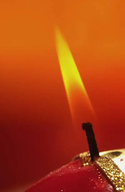 Photo of Flame of a burning holiday candle on a red background
