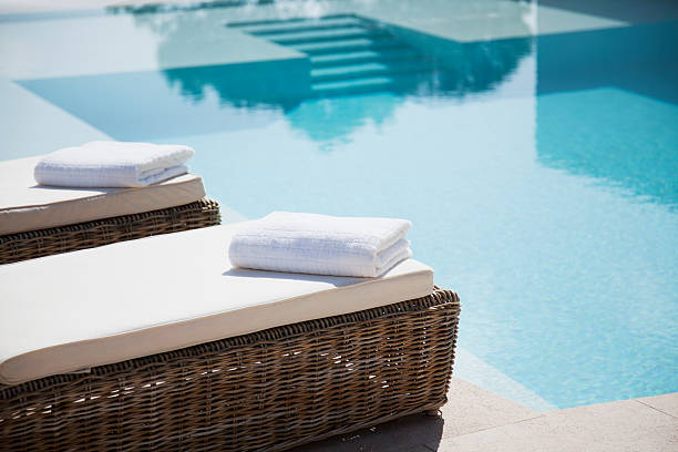 doblado toallas en sillas reclinables junto a la piscina - spa fotografías e imágenes de stock
