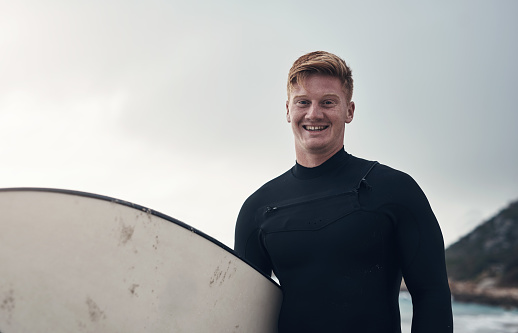 Cropped shot of a man holding his surfboard while at the beach
