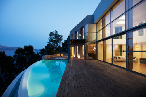 Luxurious villa with private swimming pool and chaise lounges in dusk.