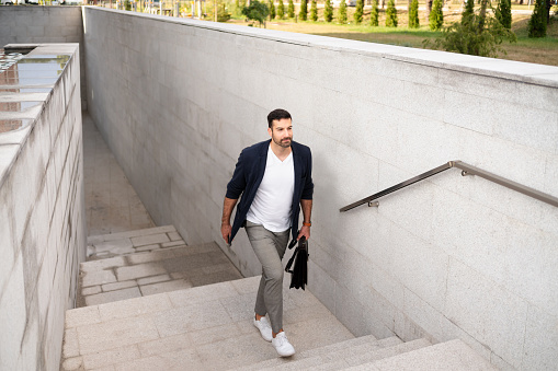 Modern young Caucasian businessman moving upstairs on his way to work.