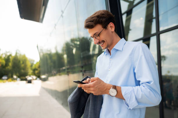 istock Smiling young businessman texting on his phone 1304083923