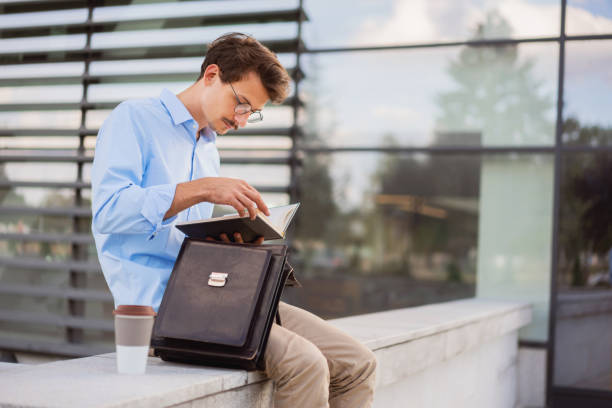 istock Young man sitting outside and looking at his notepad 1304083945