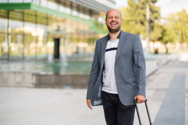 istock Portrait smiling immigrant standing outside with a suitcase and looking at the camera 1304083948