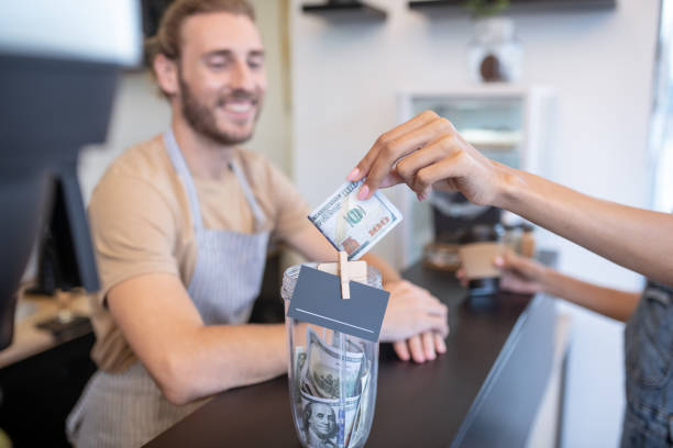 istock Womans hand holding out hundred dollar bill 1304084055