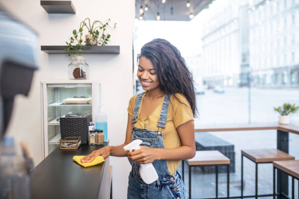 istock Young dark-haired woman wiping table in cafe 1304084196