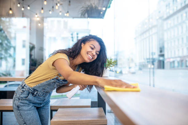 istock Young woman diligently wiping table surface 1304084201