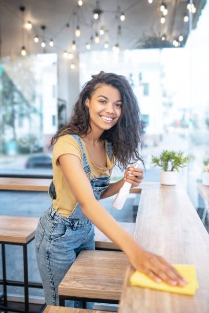 istock Pretty cheerful woman wiping table in cafe 1304084207